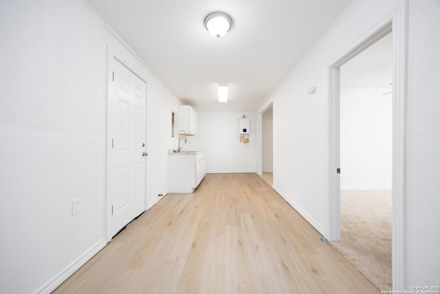 corridor with light wood-type flooring and baseboards