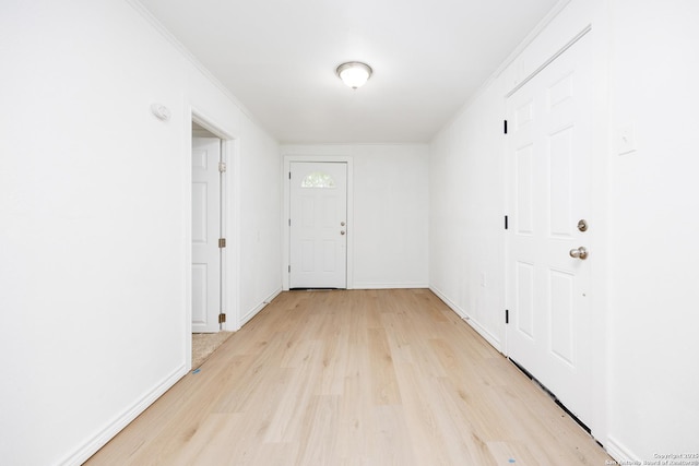 corridor featuring crown molding, light wood finished floors, and baseboards