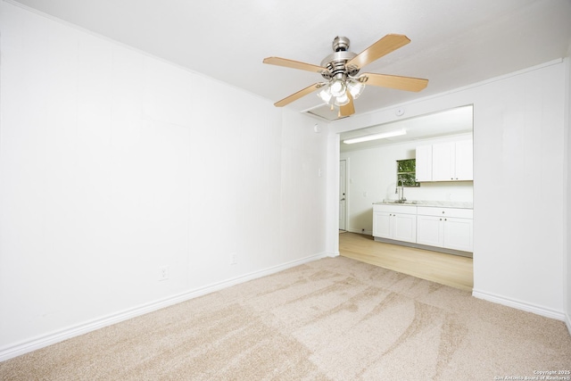 spare room featuring a sink, baseboards, light carpet, and a ceiling fan