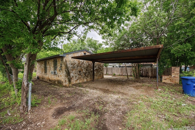 view of car parking featuring fence, a detached carport, dirt driveway, and cooling unit
