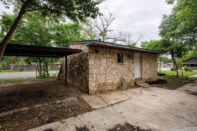 view of outbuilding featuring entry steps, fence, and a carport
