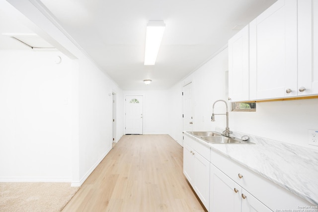 kitchen with a sink, baseboards, white cabinets, and light wood finished floors