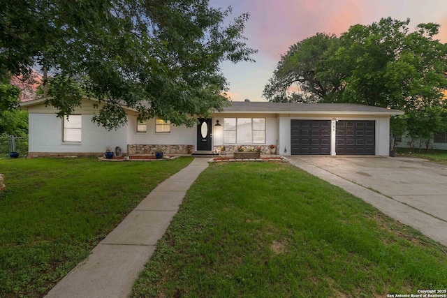 ranch-style house with a garage, stone siding, stucco siding, a lawn, and driveway