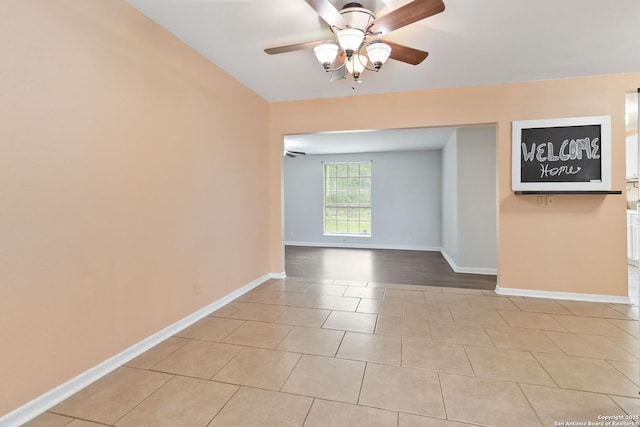 spare room featuring a ceiling fan, baseboards, and light tile patterned flooring