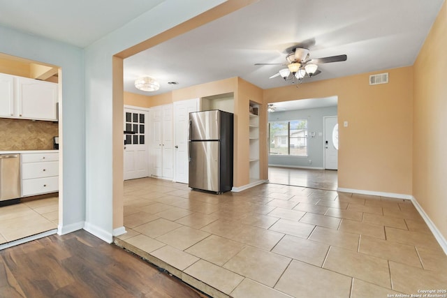 kitchen featuring visible vents, baseboards, ceiling fan, white cabinets, and stainless steel appliances