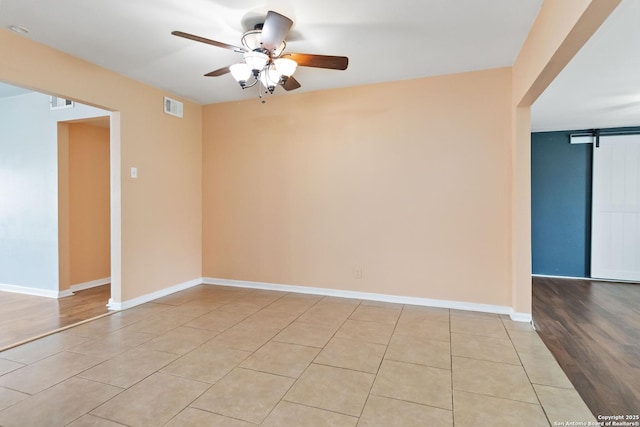 189 National, Universal City, TX 78148 - unfurnished room with visible vents, baseboards, a barn door, a ceiling fan, and light tile patterned floors