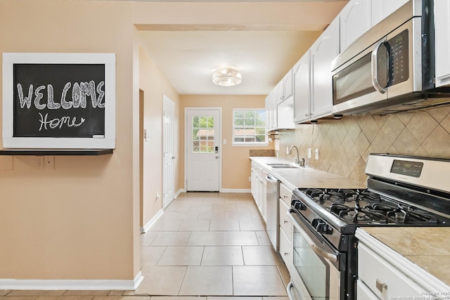 kitchen with backsplash, a sink, baseboards, white cabinets, and stainless steel appliances