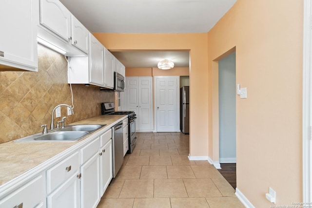 kitchen with stainless steel appliances, baseboards, white cabinetry, and a sink