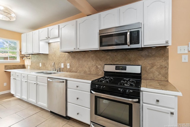 kitchen with light tile patterned flooring, white cabinetry, a sink, backsplash, and stainless steel appliances