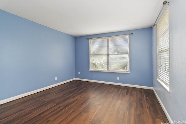spare room featuring baseboards, a healthy amount of sunlight, and wood finished floors