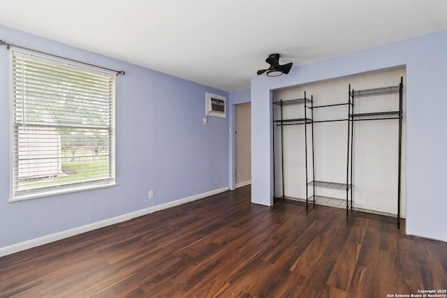 unfurnished bedroom with baseboards, wood finished floors, and an AC wall unit