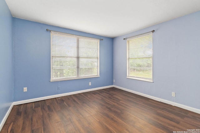 unfurnished room featuring baseboards, dark wood finished floors, and a healthy amount of sunlight
