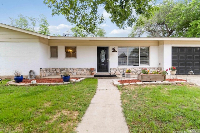 property entrance featuring a garage, a yard, and stone siding