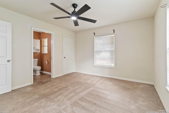 unfurnished bedroom featuring baseboards, carpet flooring, connected bathroom, and ceiling fan
