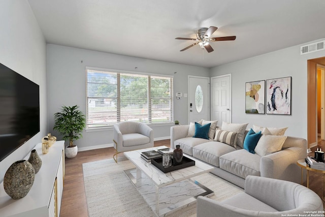 living room featuring baseboards, ceiling fan, visible vents, and wood finished floors