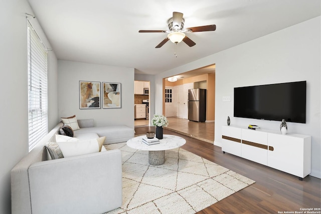 living area featuring ceiling fan, dark wood-style floors, and baseboards