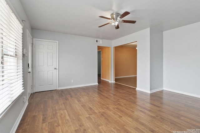 empty room with a ceiling fan, baseboards, visible vents, and wood finished floors
