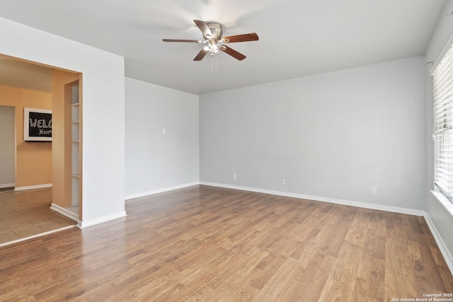 spare room featuring a ceiling fan, baseboards, and wood finished floors