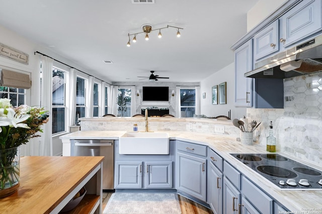 kitchen featuring a sink, black electric cooktop, a ceiling fan, a peninsula, and under cabinet range hood