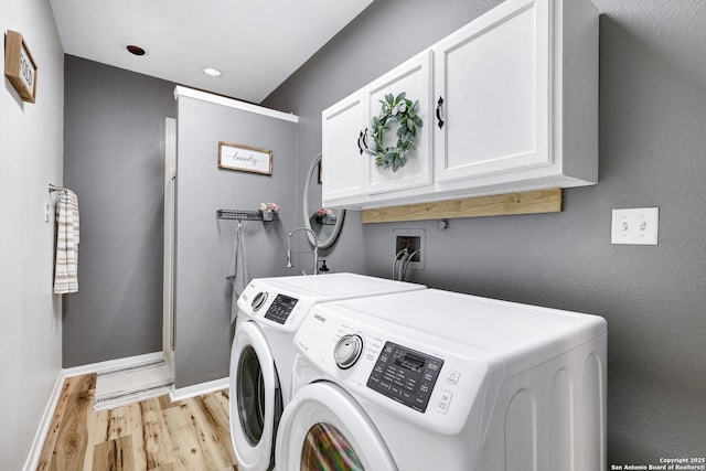 clothes washing area with cabinet space, baseboards, washer and clothes dryer, and light wood-style flooring
