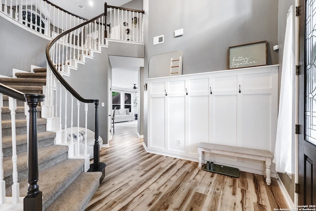 entryway with stairs, light wood finished floors, and a decorative wall