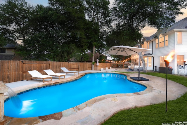 pool at dusk featuring a fenced in pool, a fenced backyard, and a patio area