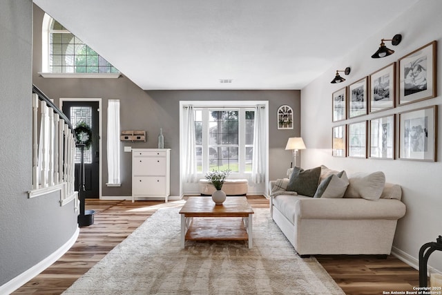 living room with stairway, baseboards, wood finished floors, and visible vents