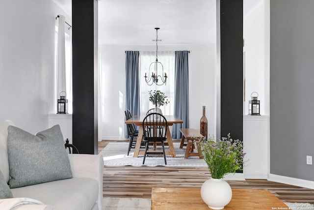 dining space with baseboards, a notable chandelier, and wood finished floors