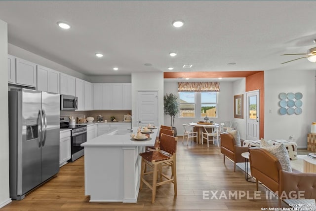 kitchen featuring a sink, wood finished floors, white cabinets, and stainless steel appliances