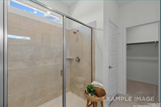 bathroom featuring a walk in closet, tile patterned flooring, and a stall shower