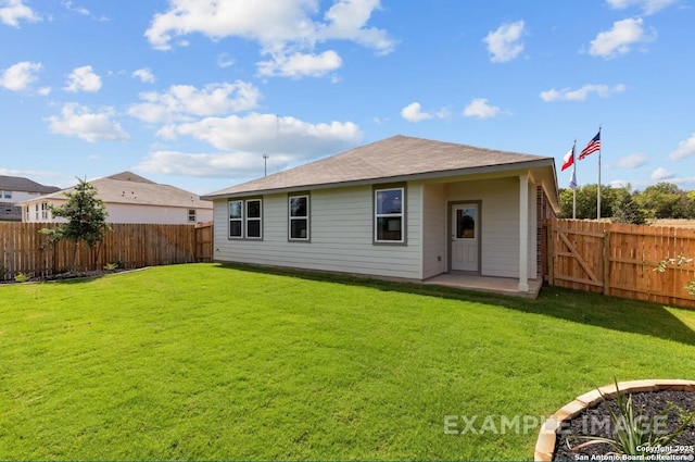 back of house with a lawn and a fenced backyard