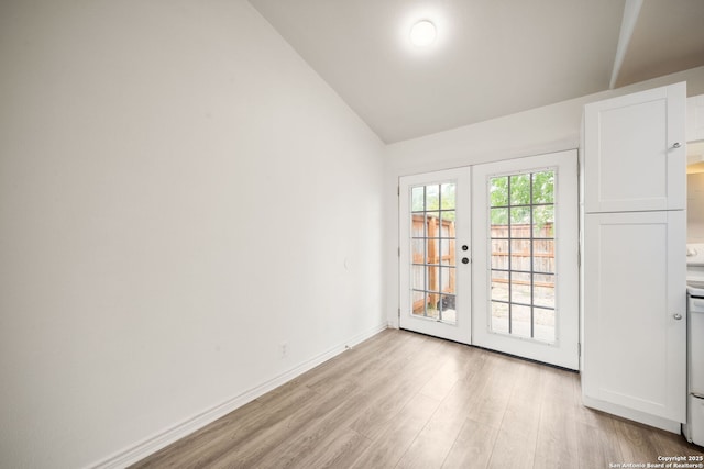 spare room with vaulted ceiling, baseboards, light wood-style floors, and french doors