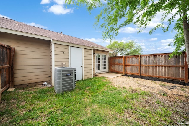 view of yard featuring a fenced backyard, central air condition unit, and french doors