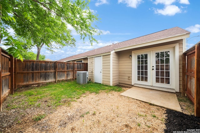 rear view of property featuring central air condition unit, roof with shingles, a fenced backyard, and french doors