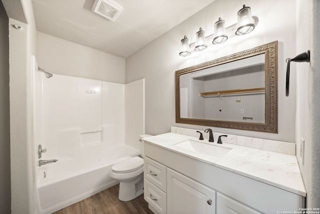 full bath featuring vanity, toilet, wood finished floors,  shower combination, and visible vents