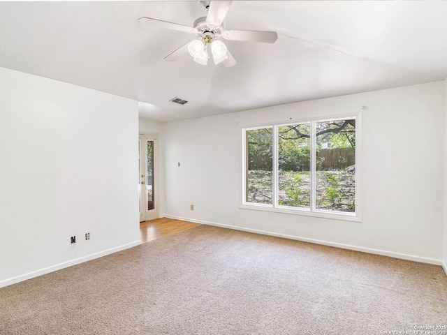 empty room with baseboards, visible vents, ceiling fan, and light colored carpet