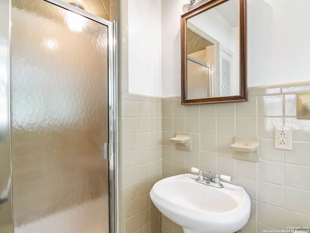 bathroom with a sink, tile walls, a wainscoted wall, and a stall shower