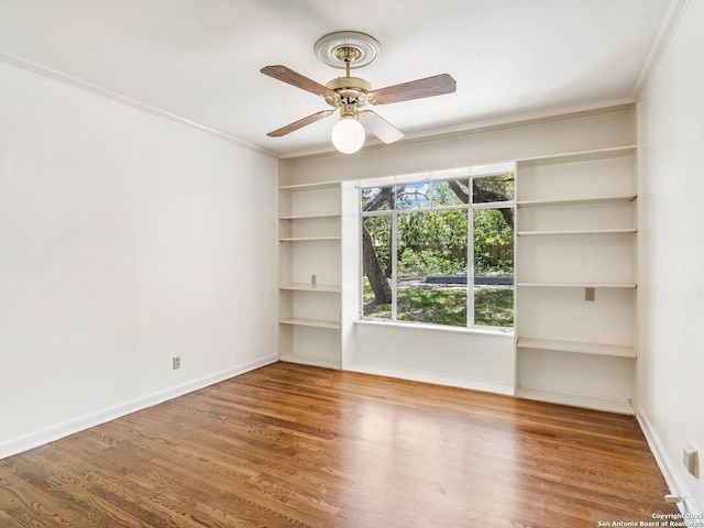 empty room featuring crown molding, baseboards, ceiling fan, and wood finished floors