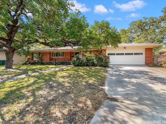 ranch-style house with fence, an attached garage, brick siding, a front yard, and concrete driveway