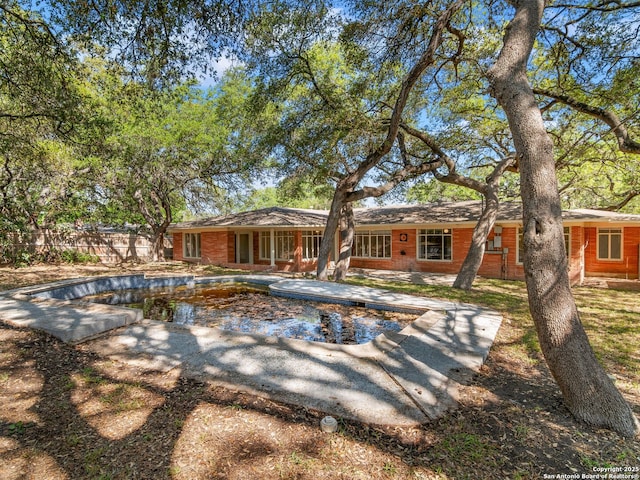 back of house with brick siding, fence, a fenced in pool, and a patio