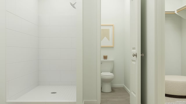 bathroom featuring baseboards, a shower stall, toilet, and wood finished floors