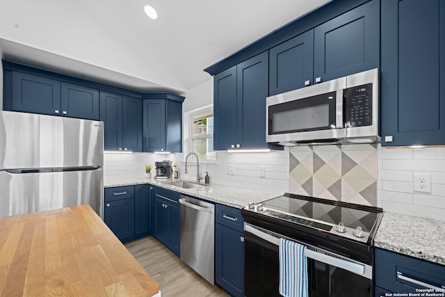 1880 Trail Pass Dr, Canyon Lake, TX 78133 - kitchen featuring appliances with stainless steel finishes, a sink, light wood finished floors, backsplash, and blue cabinets