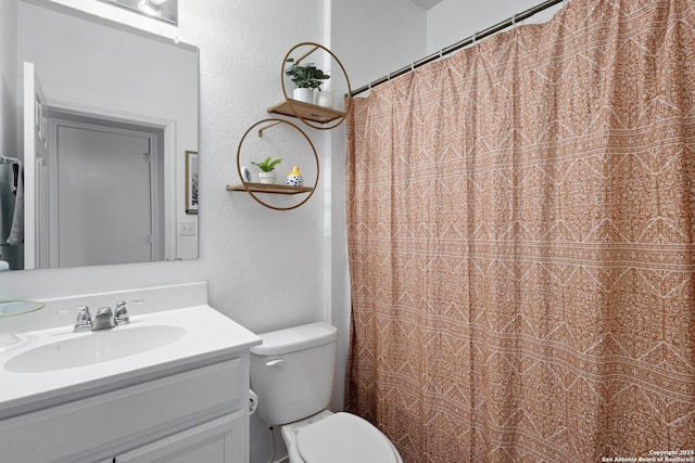 full bath featuring vanity, a textured wall, and toilet