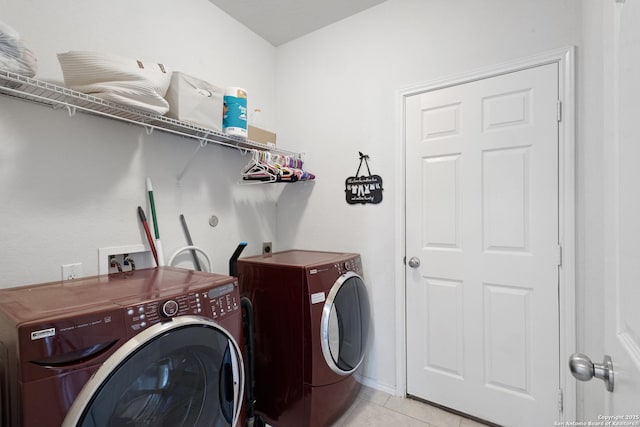 laundry area featuring laundry area, washer and clothes dryer, baseboards, and light tile patterned flooring