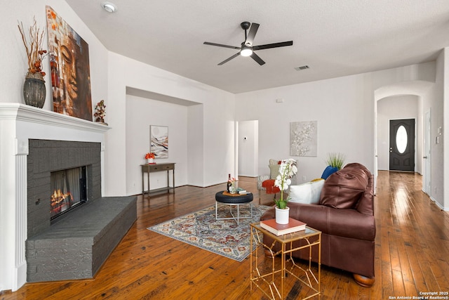 living room with a ceiling fan, arched walkways, visible vents, and hardwood / wood-style flooring