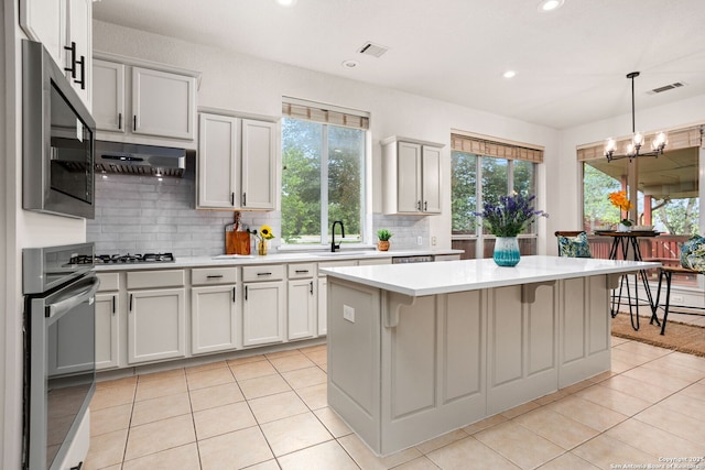 kitchen featuring appliances with stainless steel finishes, a sink, light countertops, light tile patterned floors, and backsplash