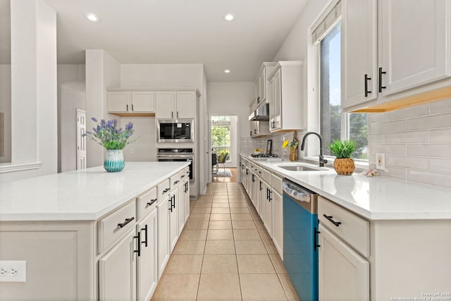 kitchen with a sink, decorative backsplash, stainless steel appliances, and white cabinetry