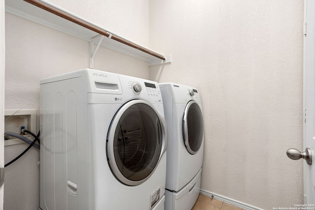laundry room with laundry area, washer and clothes dryer, and light tile patterned flooring