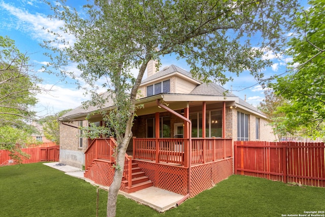rear view of house with a chimney, brick siding, a fenced backyard, a yard, and a shingled roof
