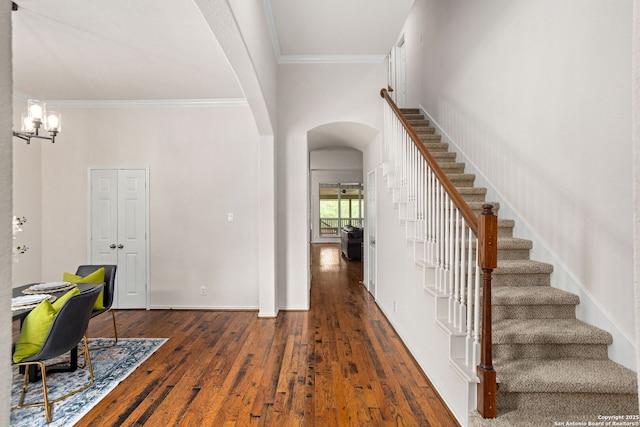 entryway featuring crown molding, an inviting chandelier, stairs, hardwood / wood-style flooring, and arched walkways
